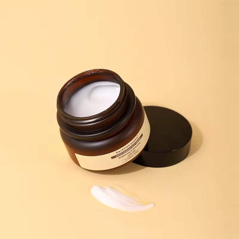 Crème de Jour Hydratante en pot brun ambré, texture blanche crémeuse et couvercle noir posé à côté