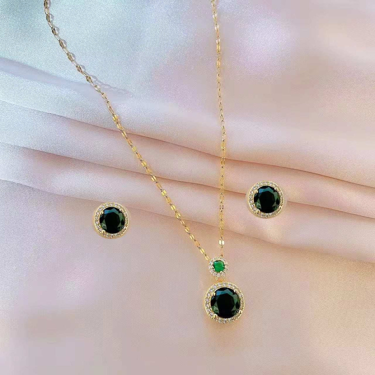 parure femme dorée en acier, collier et boucles d’oreilles avec pierres noires, détails verts et strass
